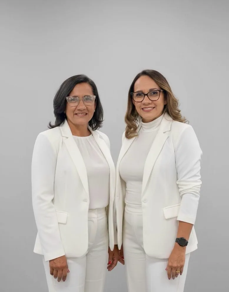 Isaira e Marcia, fundadoras da Irmãs Valentim, lado a lado, sorrindo, de blazer branco