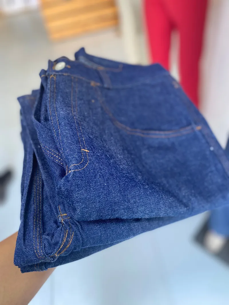 Calça jeans azul-escura dobrada, com costuras aparentes
